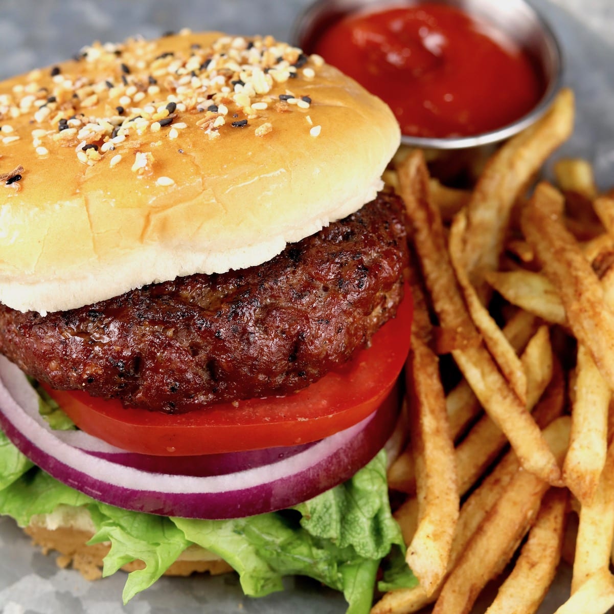 Grilled Classic Burgers with tomato, onion, lettuce on a bun served with ketchup and fries