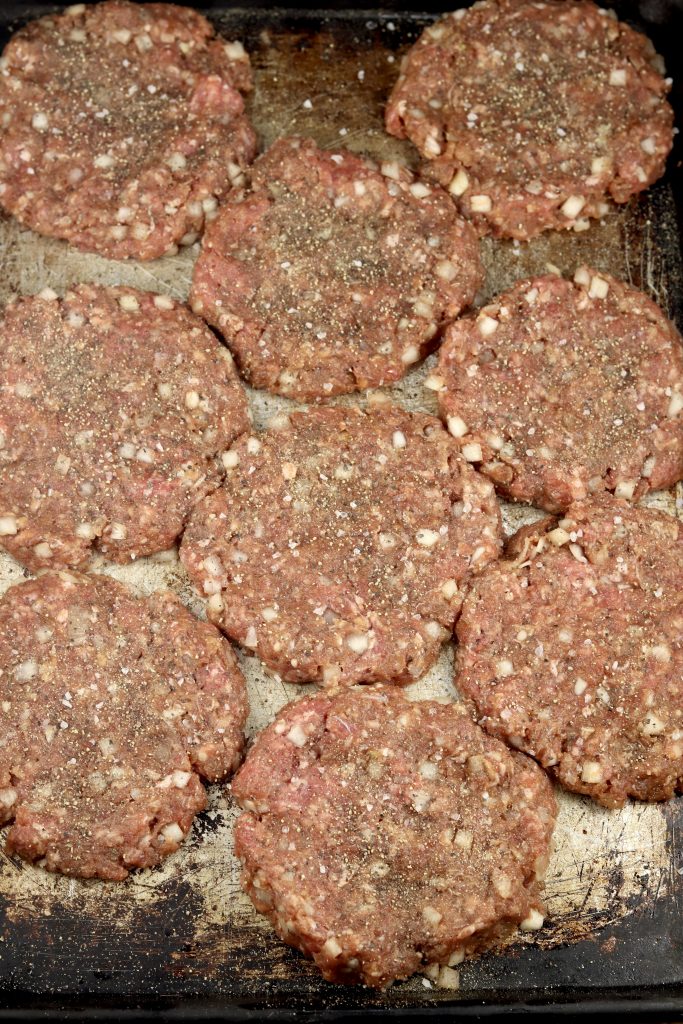 Burger Patties on a sheet pan with diced onion mixed in ready for grilling