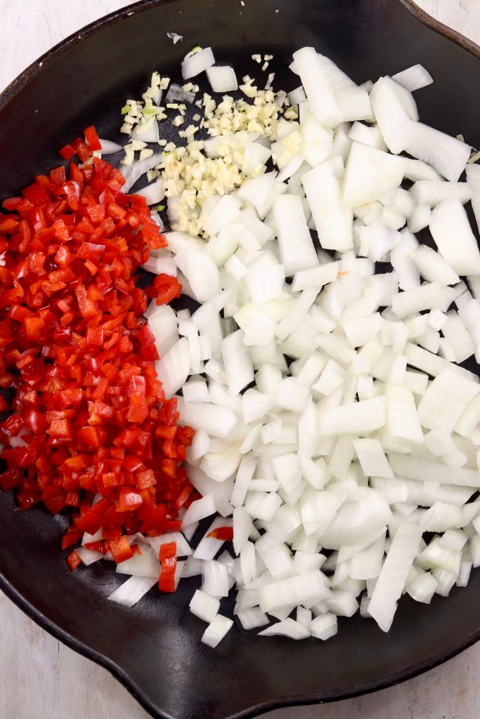 Skillet with diced red peppers, diced onion and minced garlic