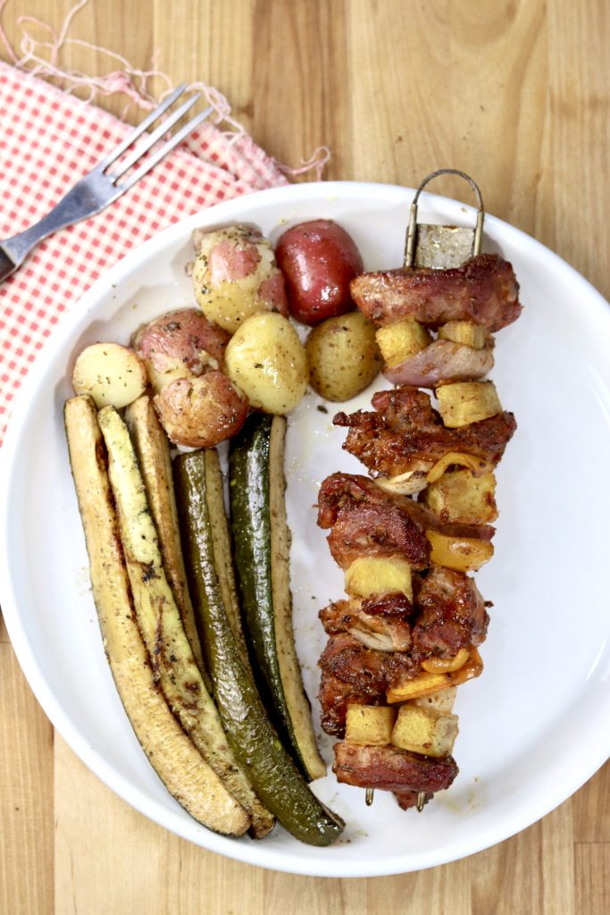 Plated pork and pineapple kabobs with grilled zucchini and roasted baby potatoes