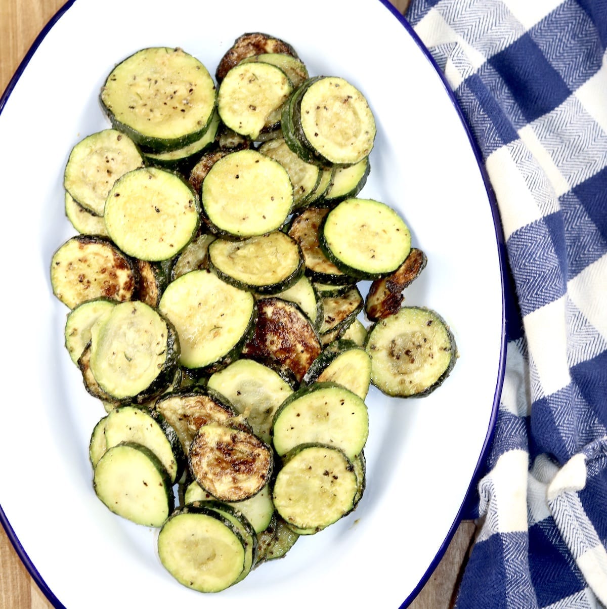 Grilled Zucchini on a white oval platter - blue napkin on side