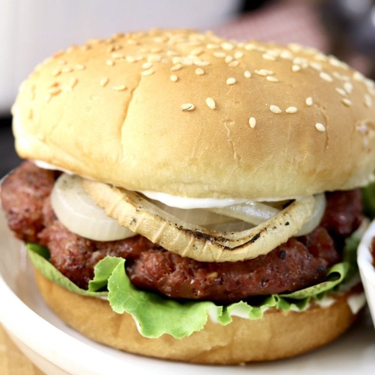Grilled Burgers on a sesame bun with lettuce and grilled onion