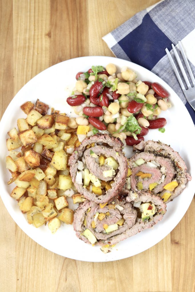 Steak Pinwheels on a plate with bean salad and roasted potatoes