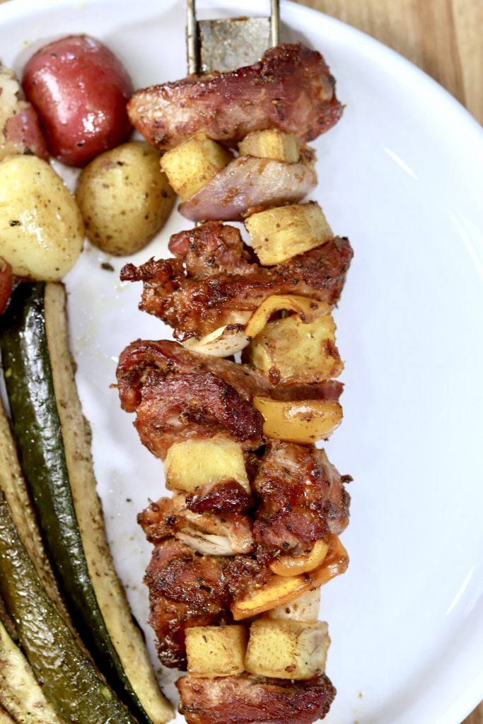 Grilled Pineapple and Pork Kabobs on a plate with potatoes and zucchini spears