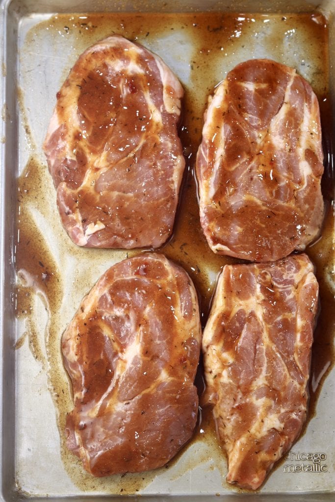Pork steaks brushed with Coca-Cola glaze on a sheet pan ready for grilling