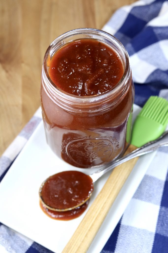 Homemade bbq sauce in a mason jar, spoonful to the side on a white plate
