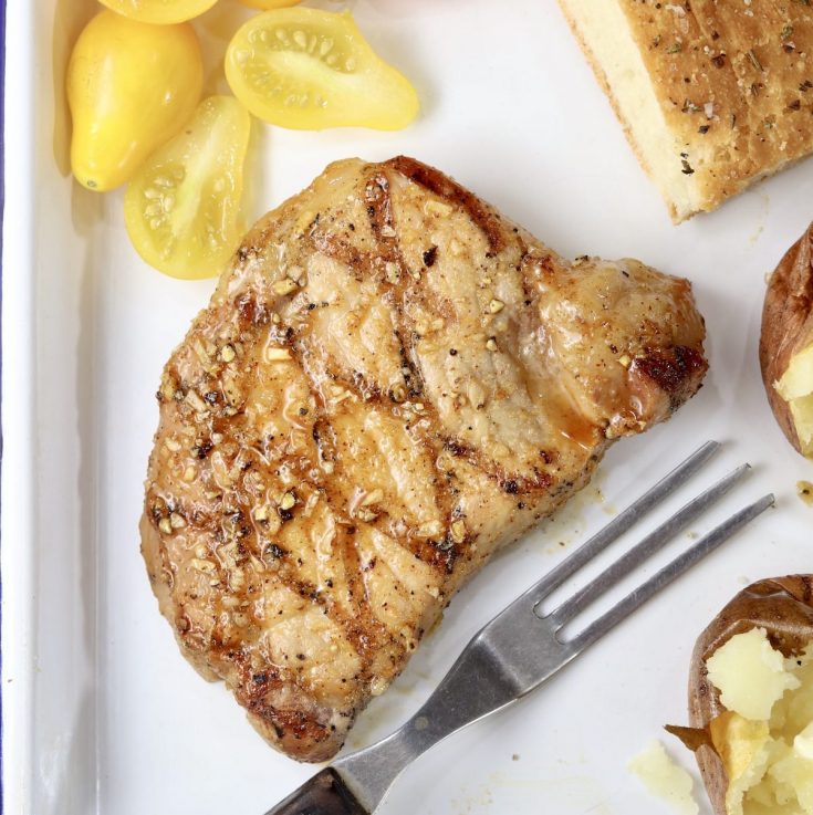 Honey BBQ Pork Chops with yellow tomatoes and a fork on a white tray