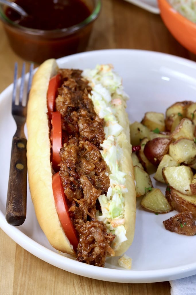 Brisket Po Boy Sandwich on a French roll with roasted potatoes - on a white plate