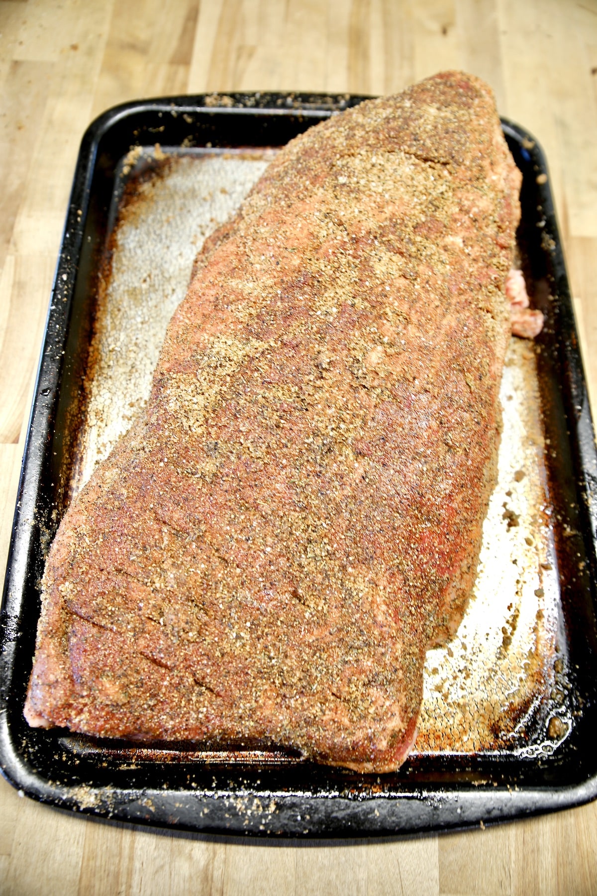 Whole brisket seasoned with dry rub ready to grill.