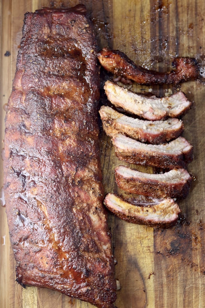 Overhead view - Rack of baby back ribs on a cutting board with sliced ribs on the side
