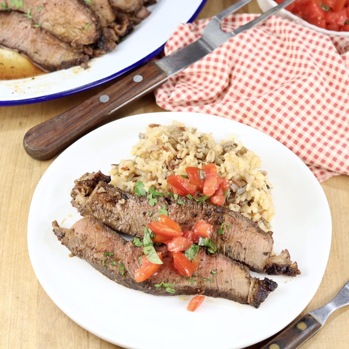 Sliced roast beef with tomato and basil garnish over rice pilaf