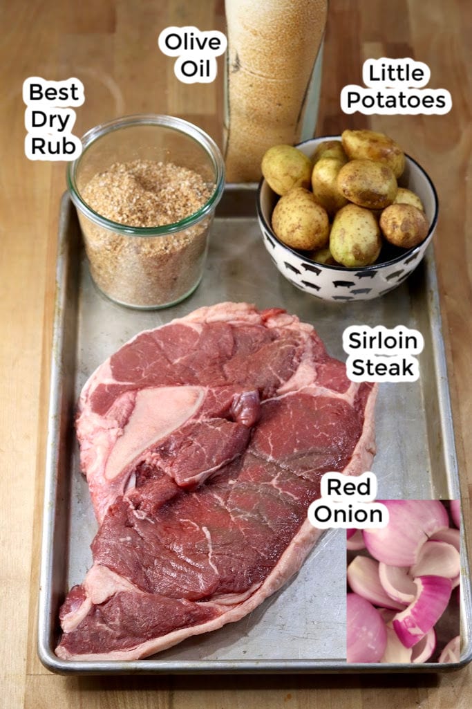 Ingredients for Steak & Potato Kabobs- Sirloin steak, little potatoes, red onion, dry rub, olive oil on a sheet pan with text labels