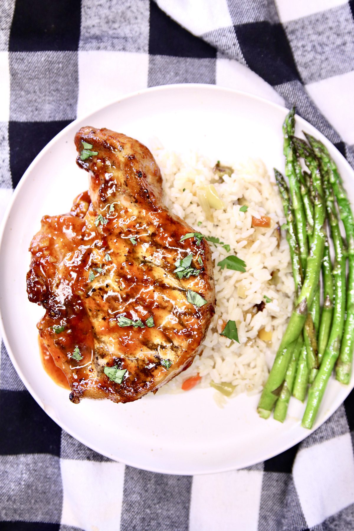 plate with bbq pork chop, rice pilaf and asparagus.