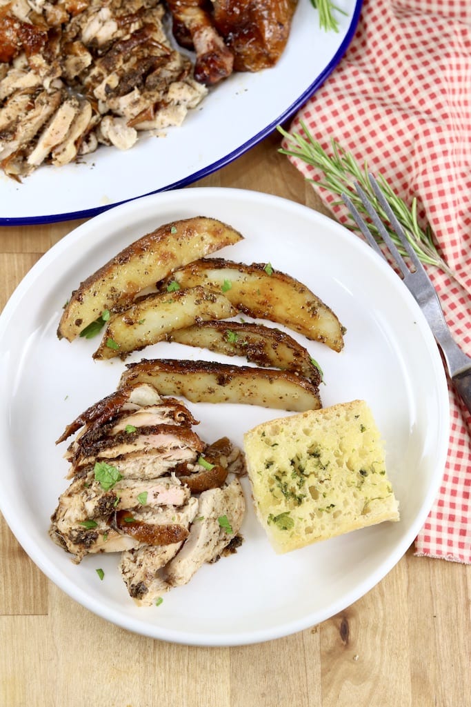 Plate of smoked chicken with potato wedges and garlic bread