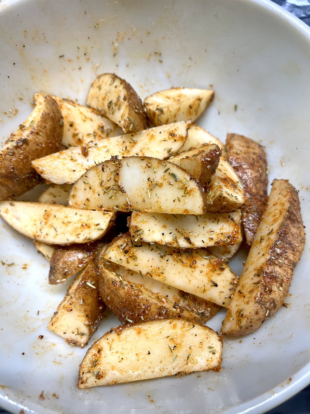Bowl of potato wedges with seasonings.