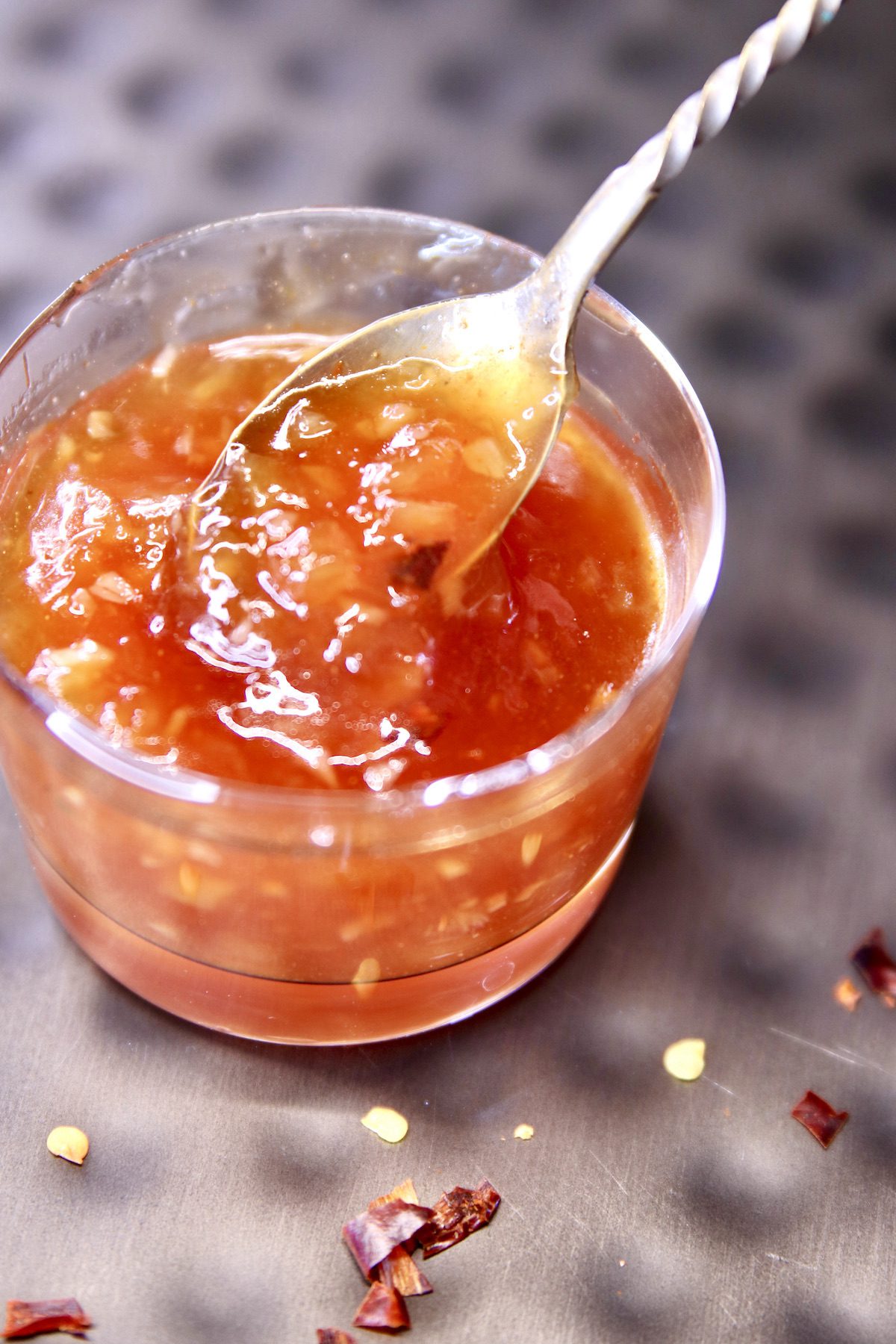 small sauce cup with pineapple bbq sauce with a spoon.