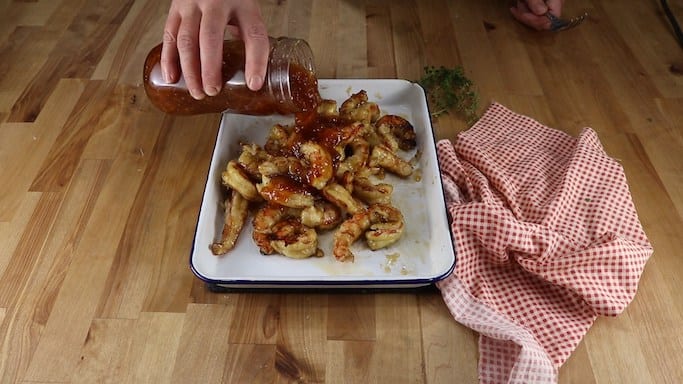 Pouring bbq sauce over grillied shrimp