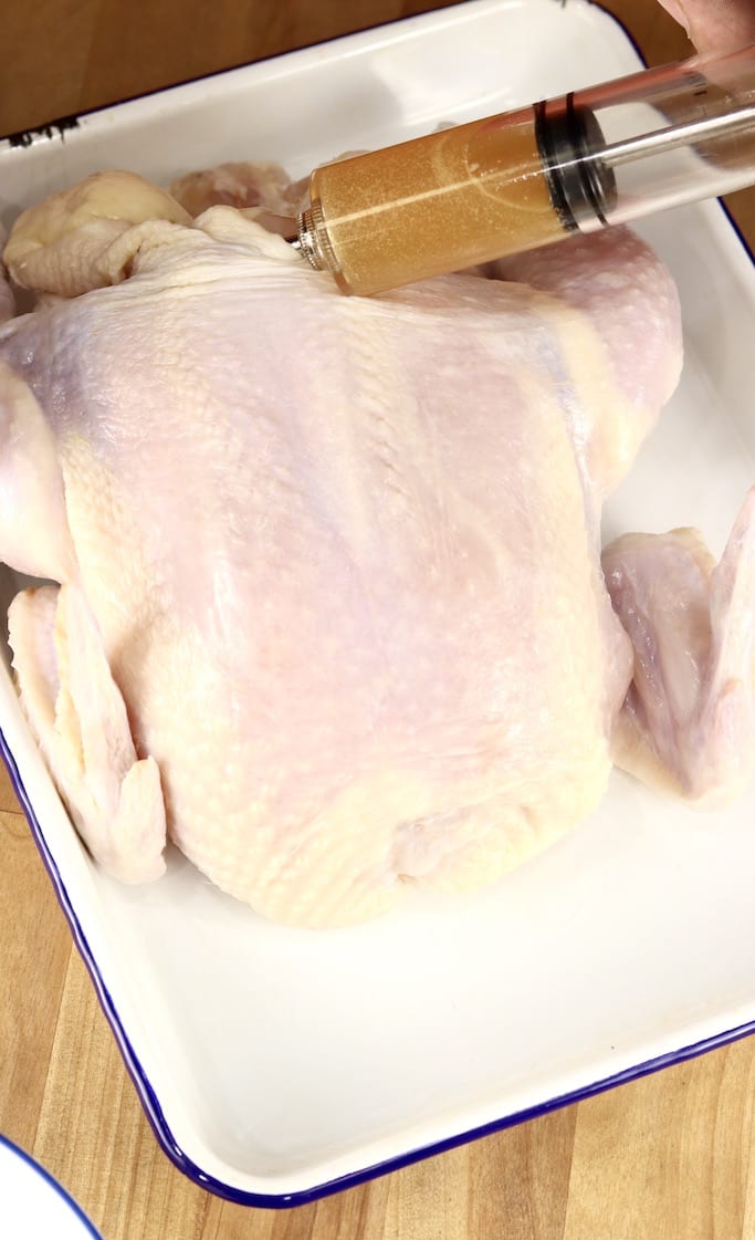 Injecting apple cider marinade into a whole chicken