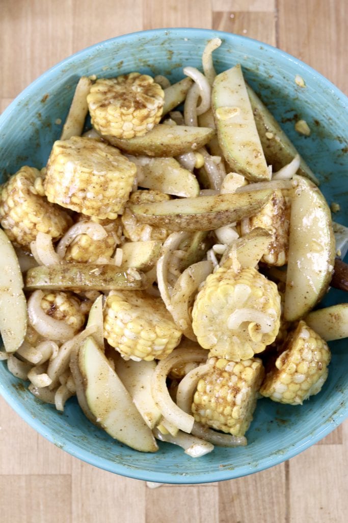 Corn on the cob chunks with potatoes and onions seasoned with Old Bay in a bowl