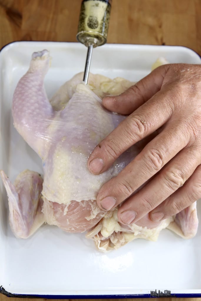 Injecting herb butter under the skin of a whole chicken