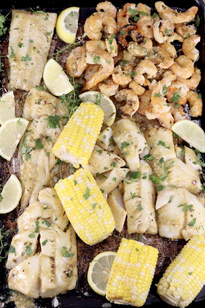 Grilled fish, shrimp and corn on a sheet pan, lemon slices