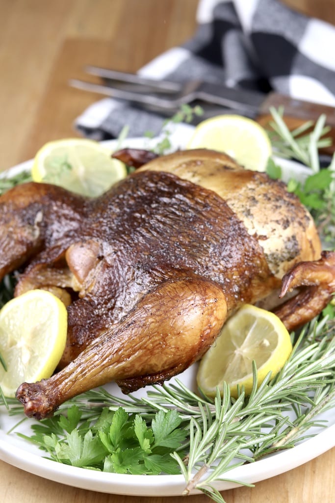Whole Chicken on a platter with lemon slices and fresh rosemary