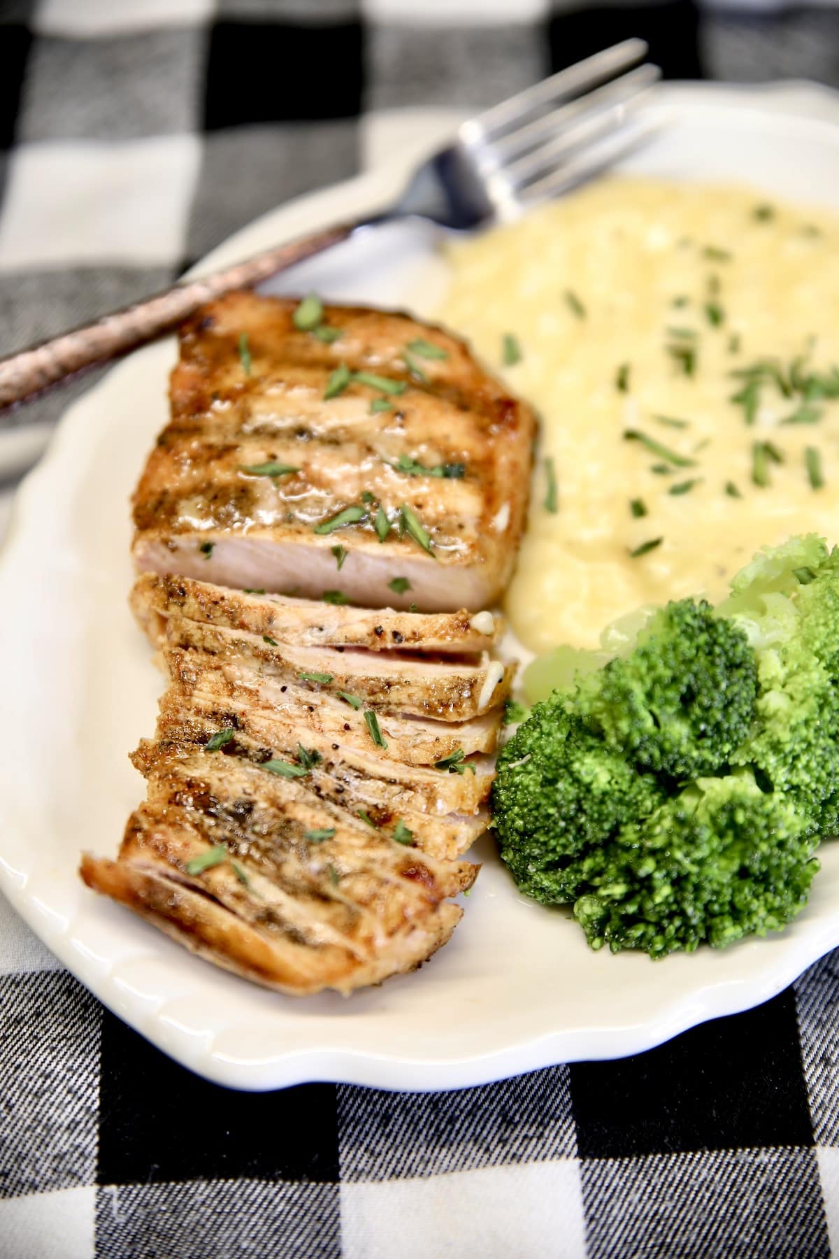 Plate with sliced pork chop, broccoli, potatoes.
