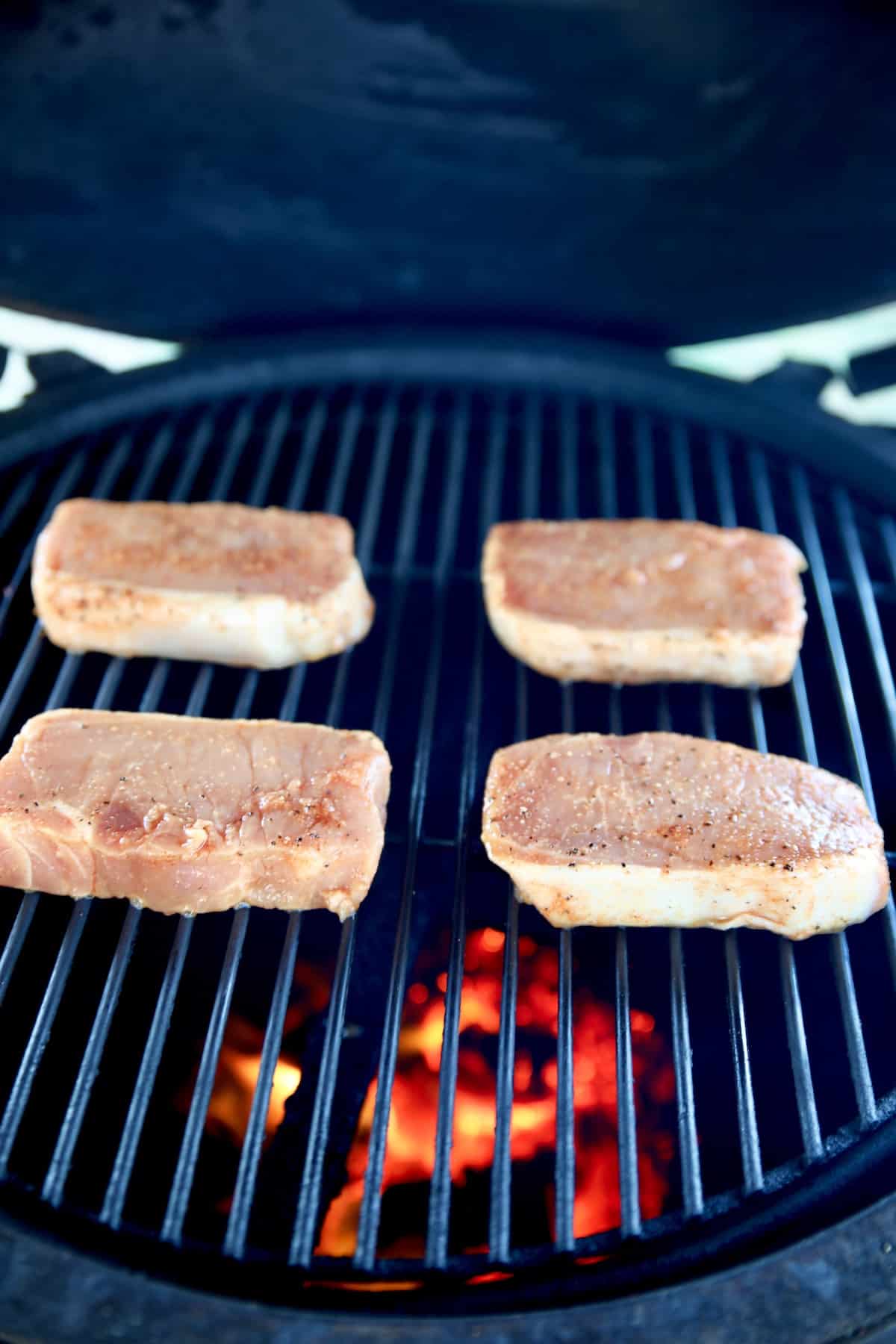 4 boneless pork chops on a grill.