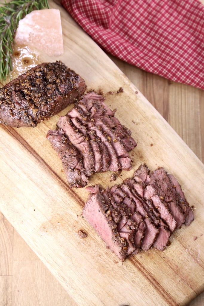 Sliced Venison Steak on a cutting board, one steak not sliced