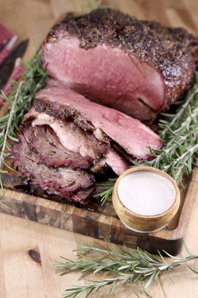 Prime Rib with horseradish Sauce on a cutting board with fresh rosemary