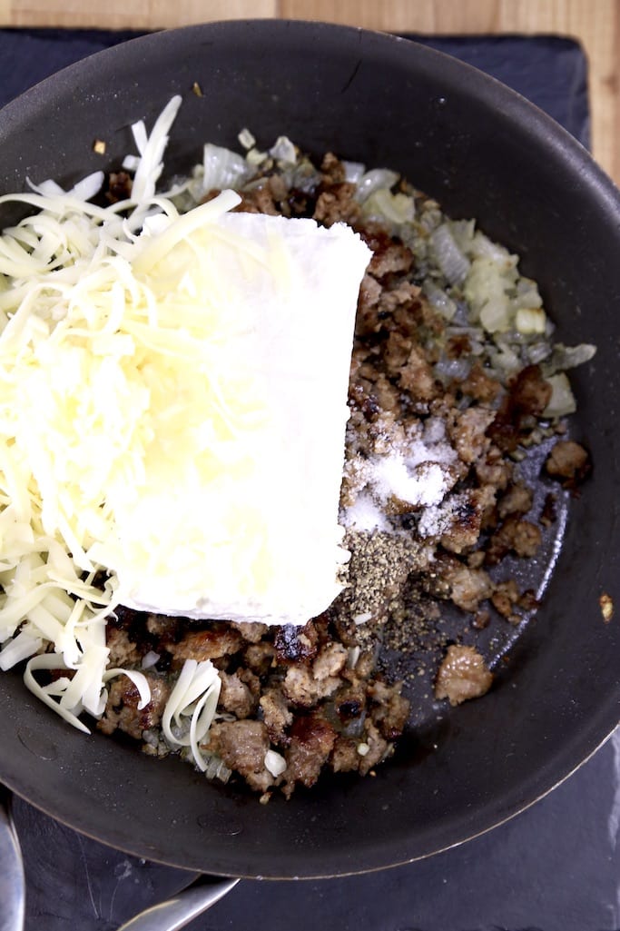 skillet with sausage, cream cheese, onions and shredded cheese