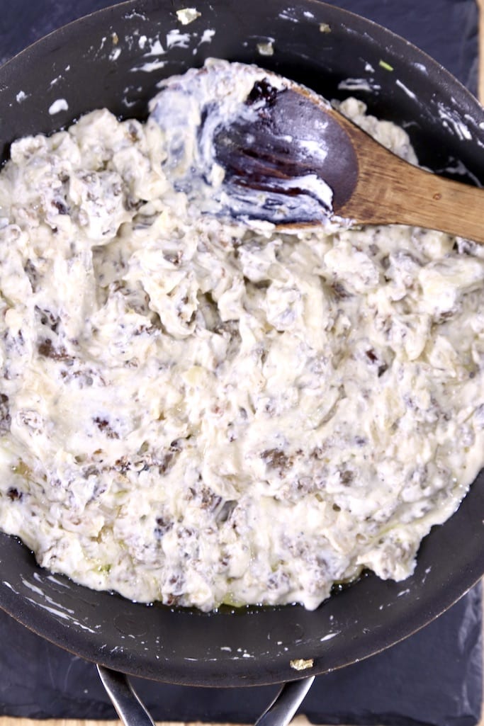 creamy sausage filling for stuffed mushrooms in skillet with wood spoon