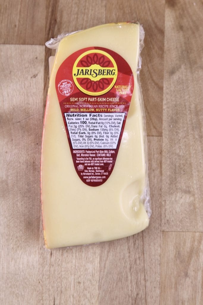 Jarlsberg Cheese in the package on a wood counter top