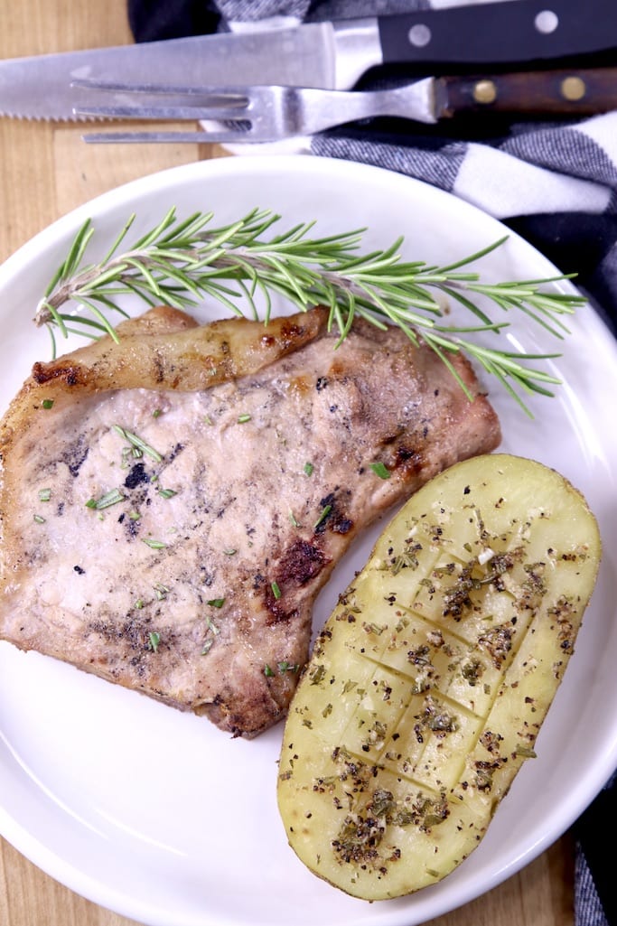 Garlic butter potato with pork chop and fresh rosemary on a plate