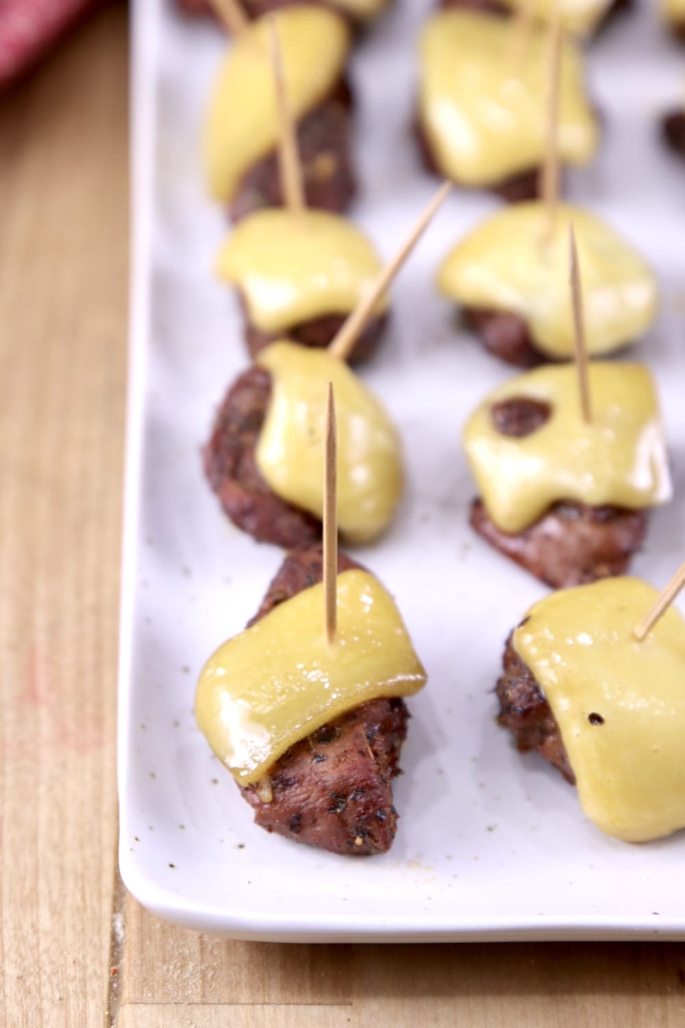 Closeup of steak bites with melted cheese on toothpicks