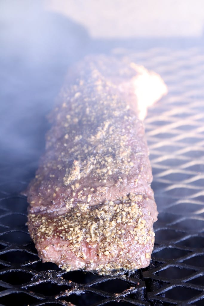 garlic glazed beef tenderloin on a grill with smoke