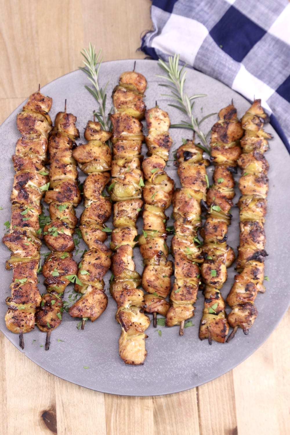 Grilled chicken skewers on a round platter, napkin to the side