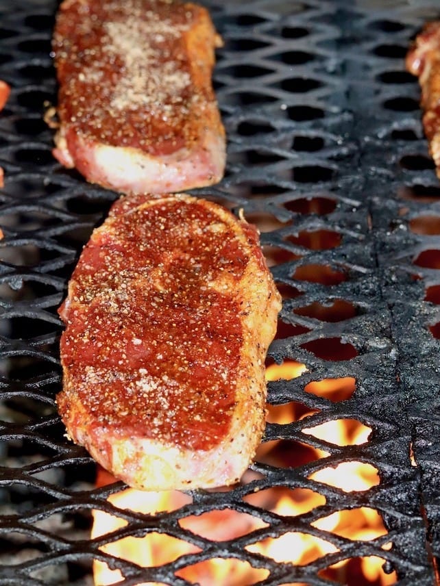 RIBEYE STEAKS ON A GRILL WITH OPEN FIRE