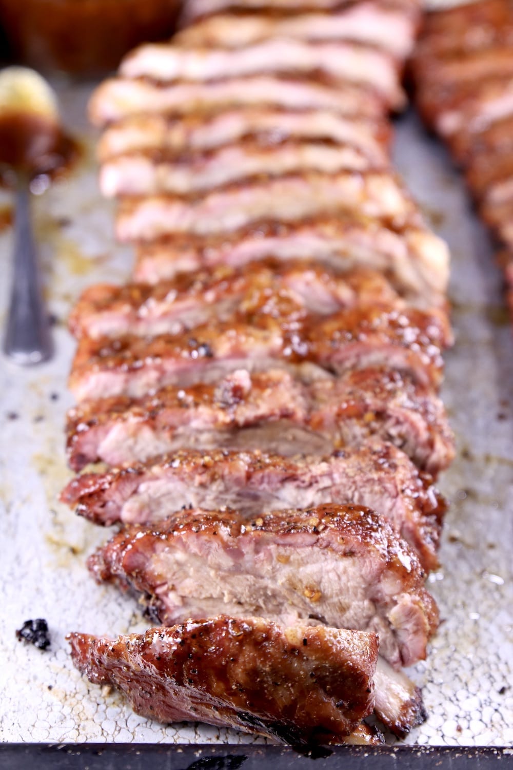 Sliced rack of barbecue baby back ribs on a sheet pan