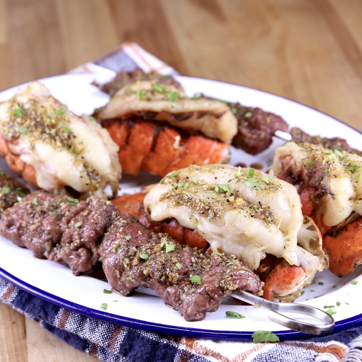 Garlic Butter Lobster Tails on a platter with steak bites