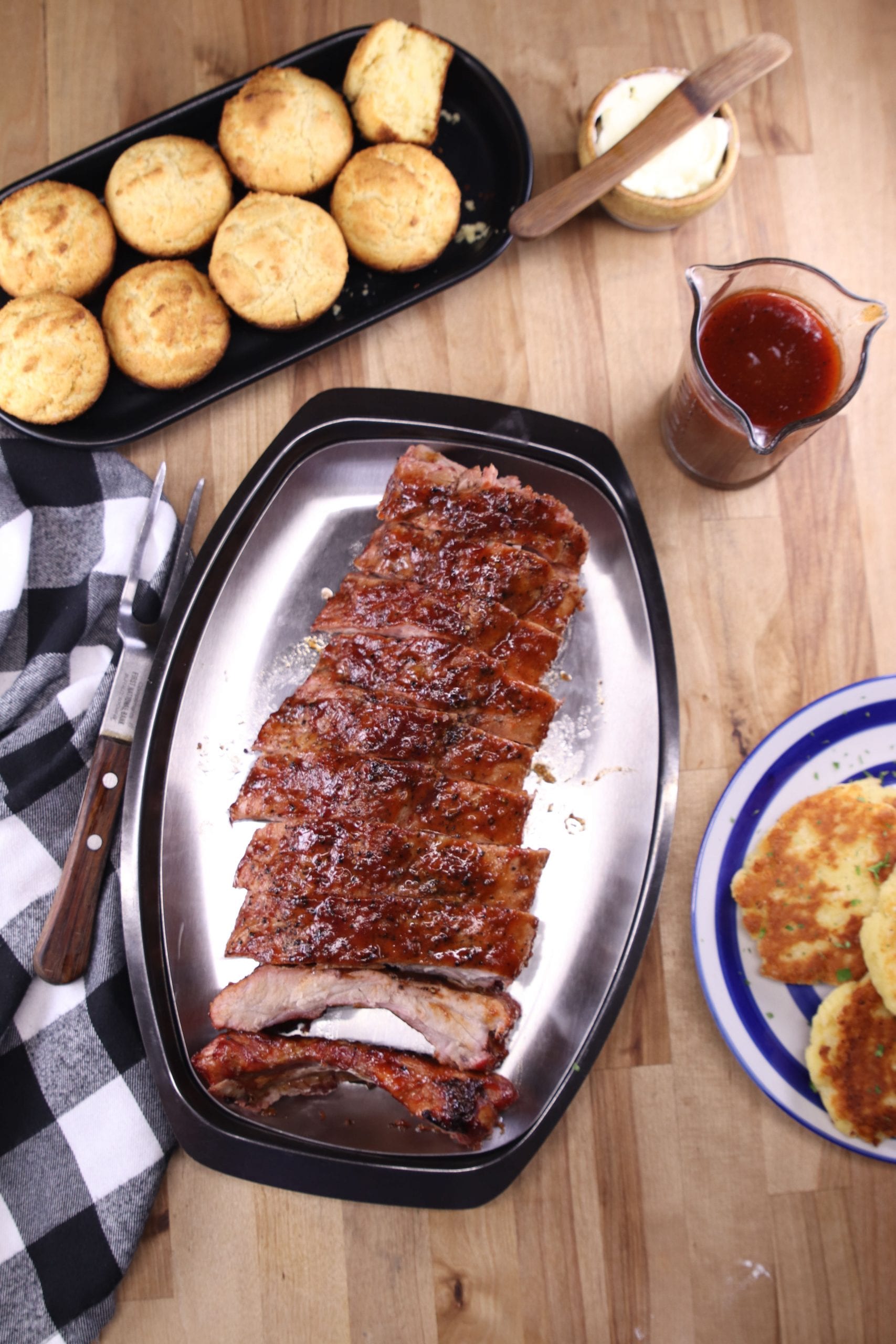 Maple BBQ Ribs on a platter with cornbread muffins and bbq sauce in a jar