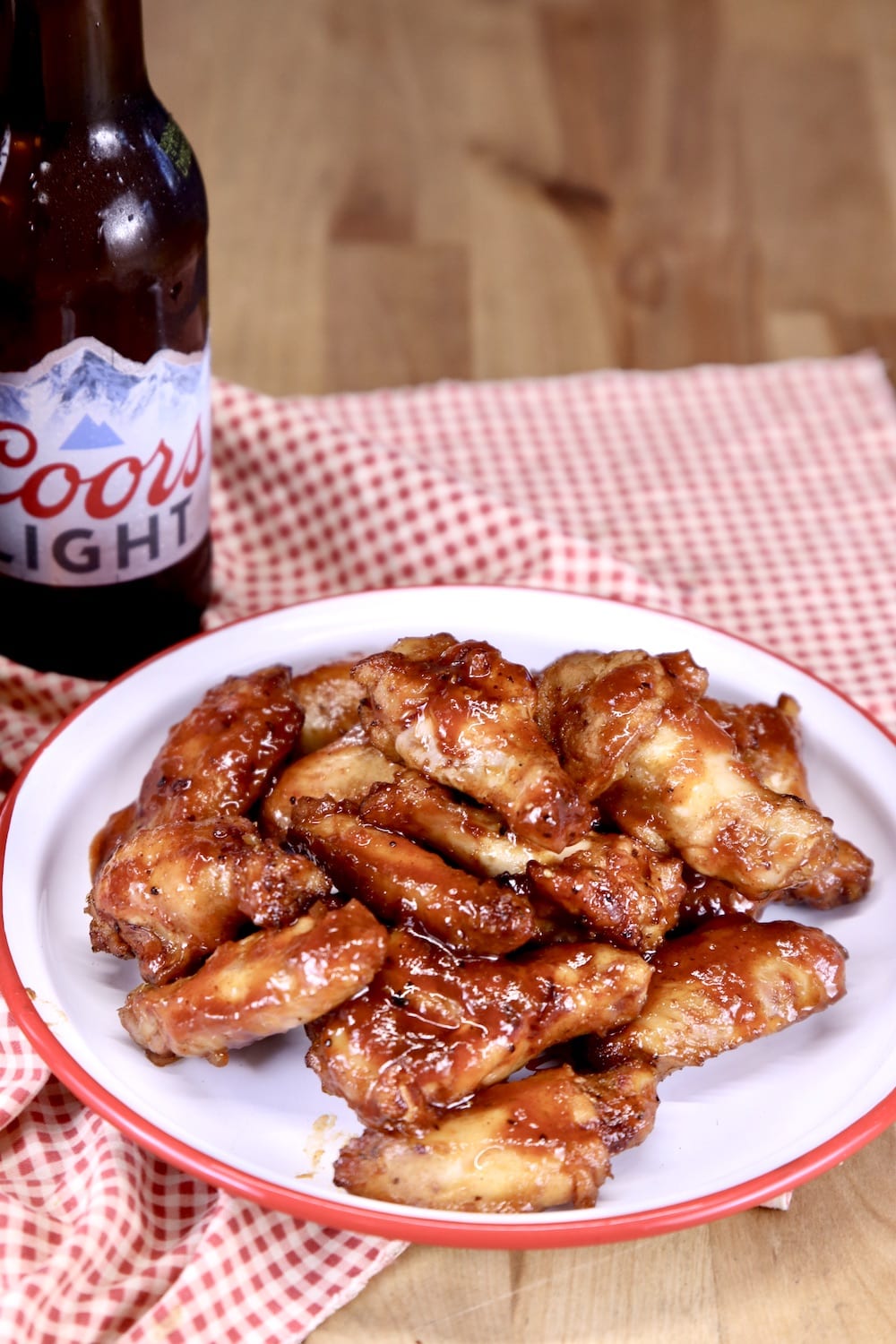Chicken wings on a plate with a bottle of Coors beer, red check napkin