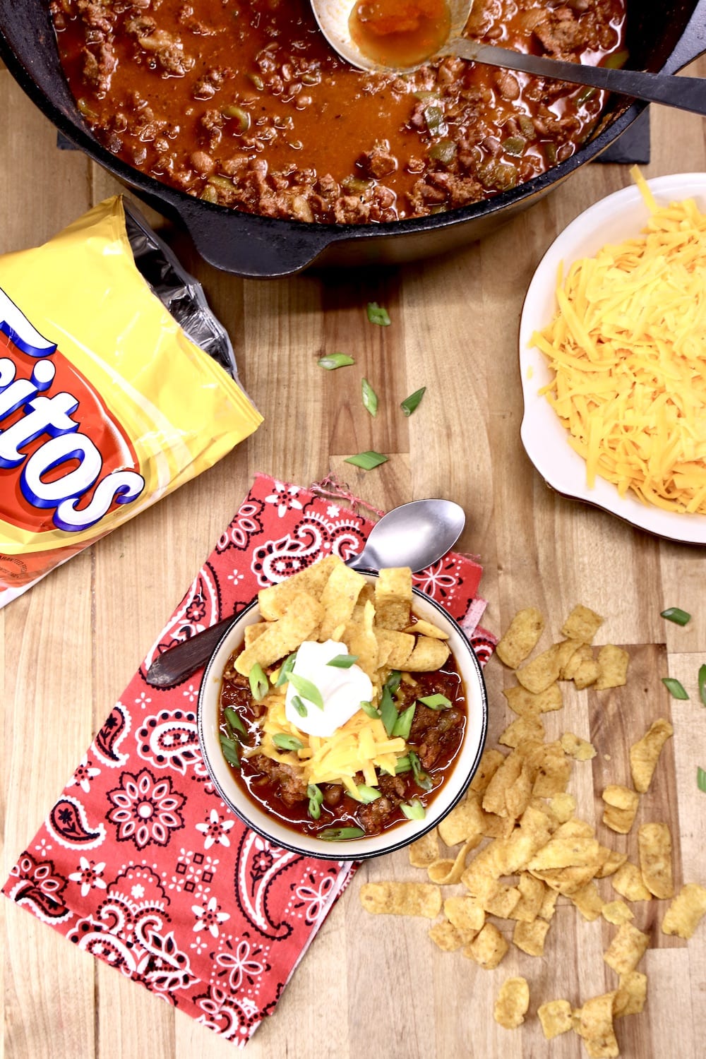 Smoked Chili: dutch oven, bowl topped with cheese, sour cream, Fritos, bag of Fritos, cheese in a bowl