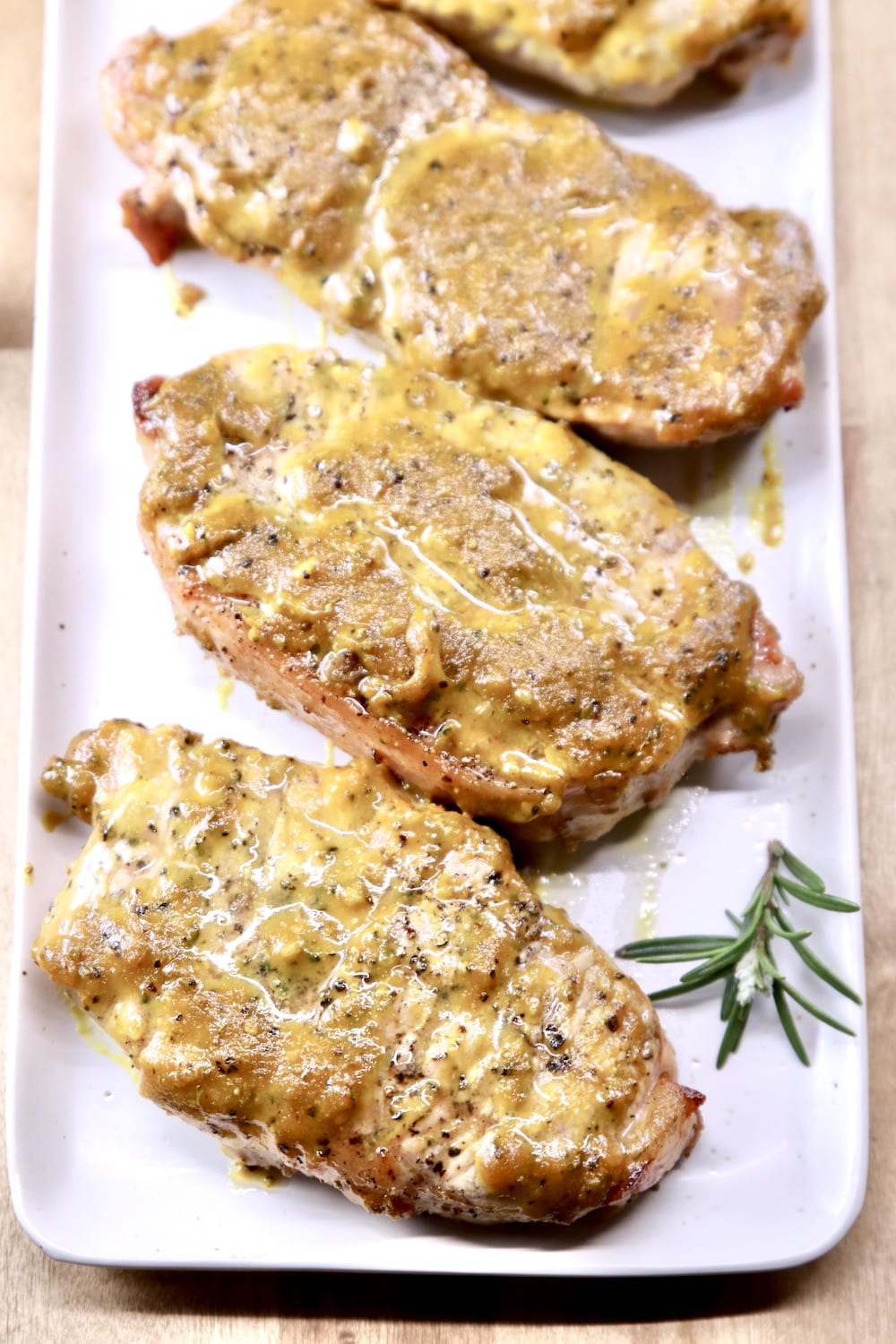 Platter of mustard grilled pork chops with sprig of rosemary