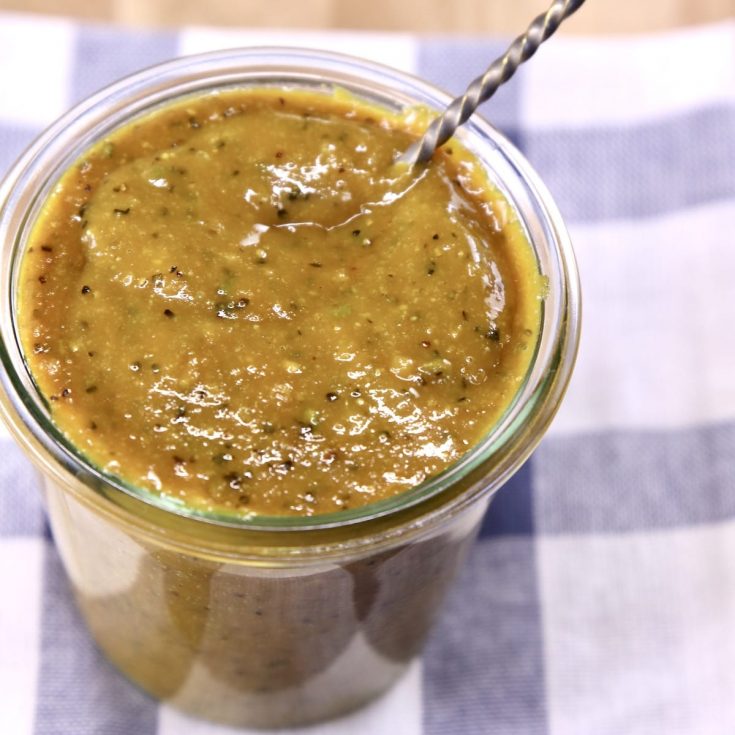 rosemary mustard bbq sauce in a jar with a spoon, sitting on a blue & white check towel