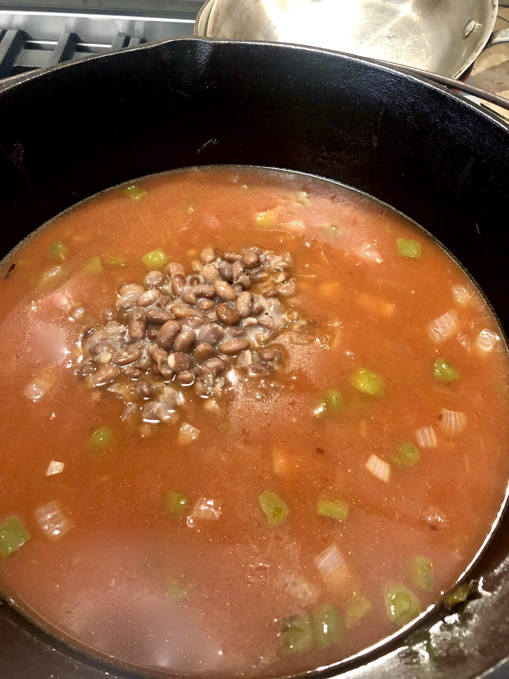 pinto beans in tomato broth with vegetables for chili in cast iron dutch oven