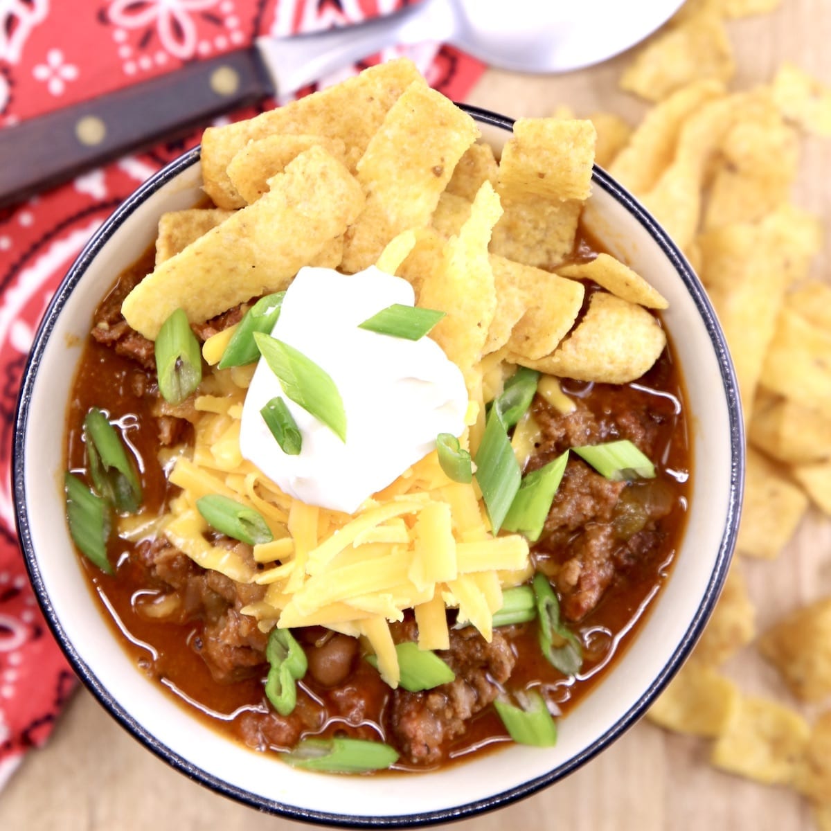 Smoked chili in a bowl with cheese, sour cream, Fritos and green onions