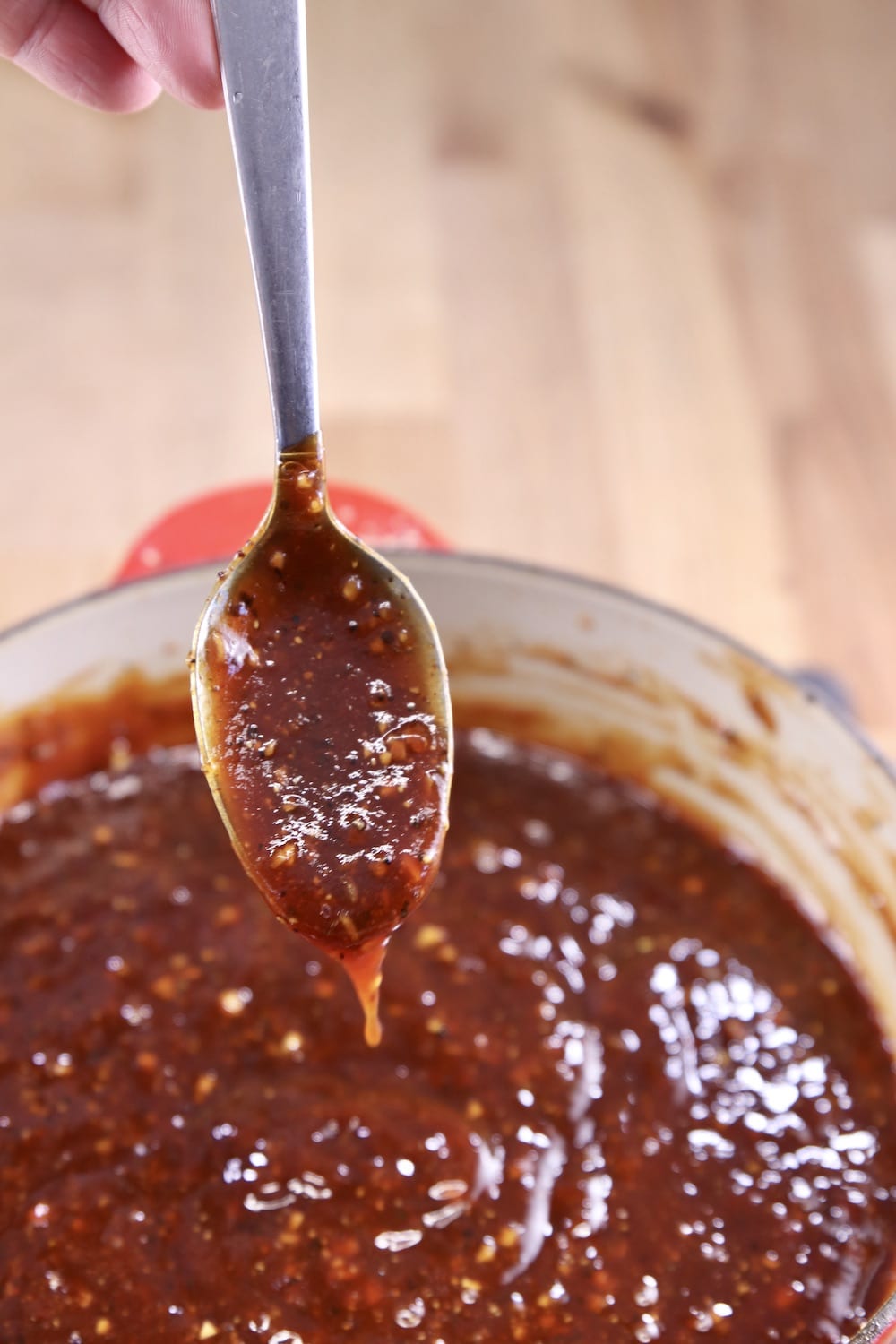 Spoon dipping into pan of bbq sauce