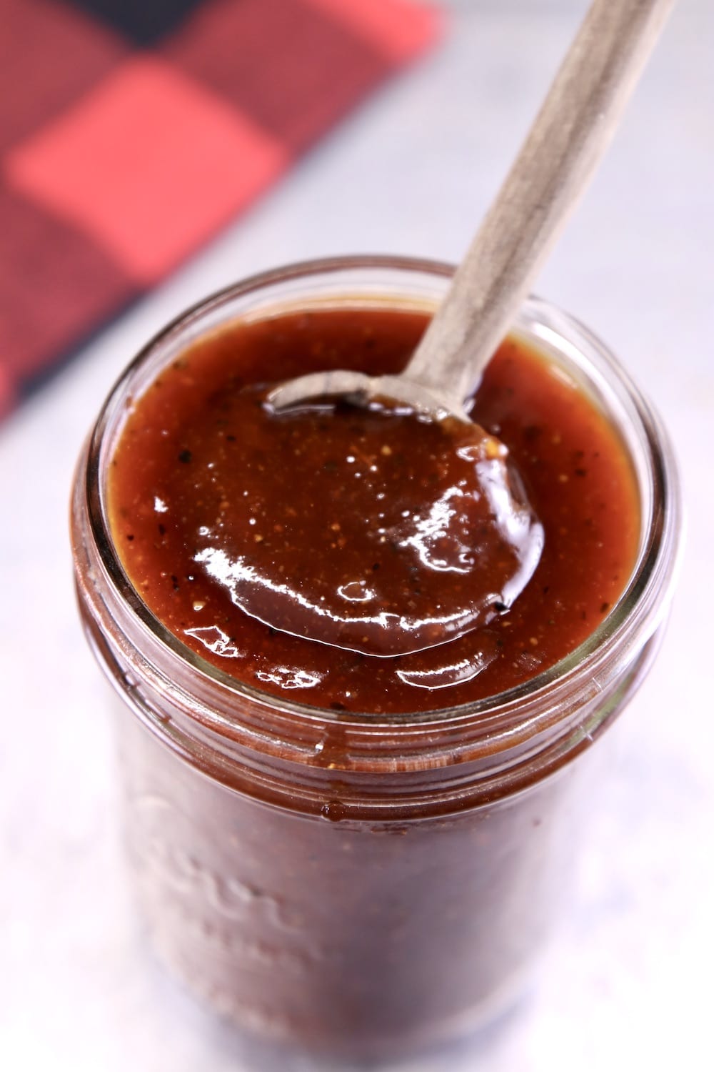 Thick bbq sauce in a jar with a wood spoon