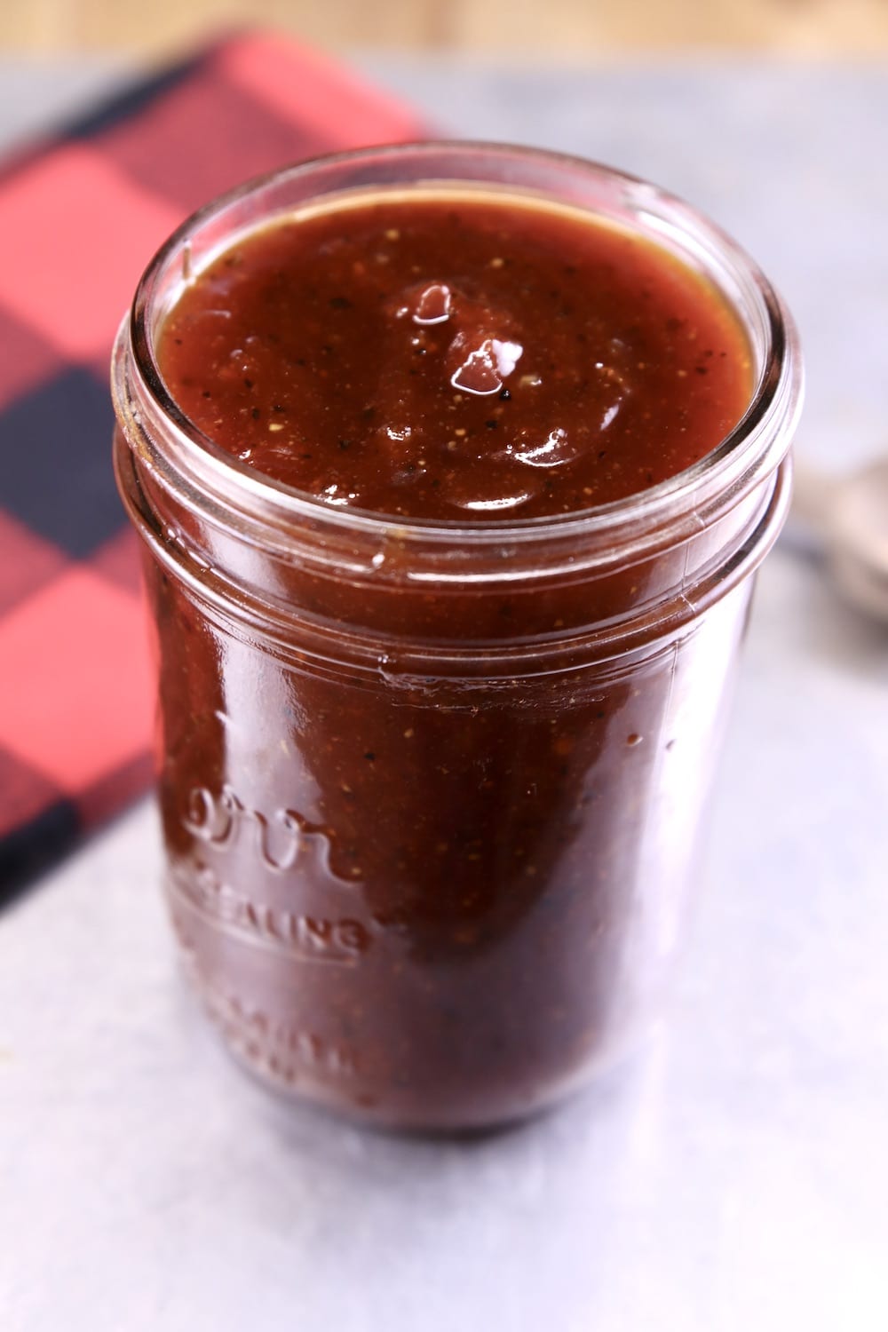 Jar of barbecue sauce with red and black check napkin